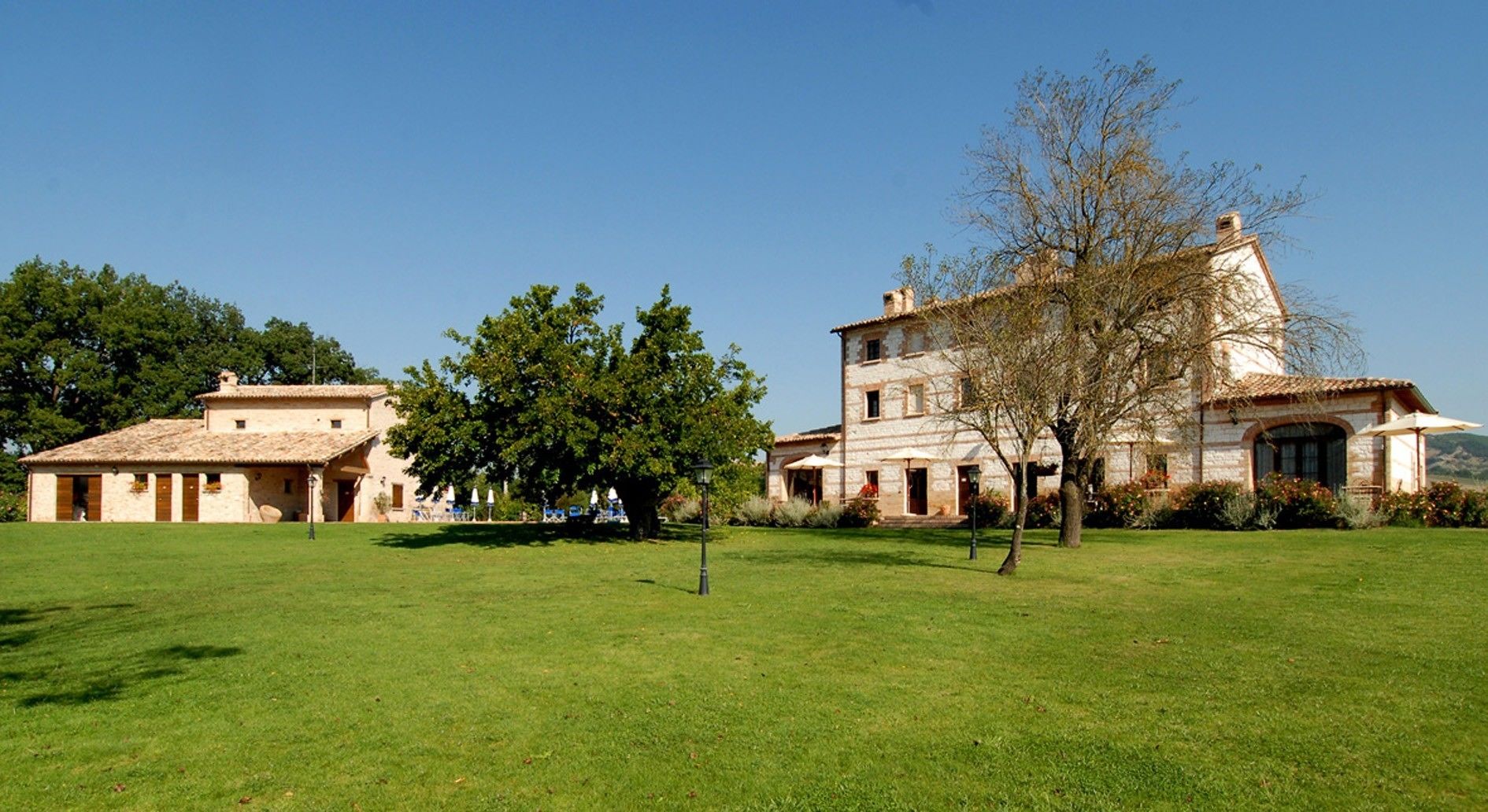 A large stone building with a tiled roof, surrounded by a well-maintained lawn and trees.