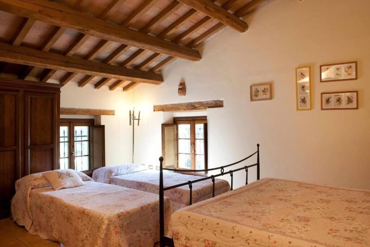 A bedroom with two beds, wooden beams on the ceiling, and framed botanical prints on the wall.