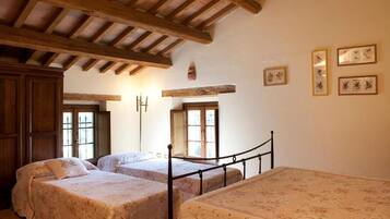 Un dormitorio con dos camas, vigas de madera en el techo e impresiones botánicas enmarcadas en la pared.