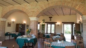 A dining area with brick arches, tables with green tablecloths, and wooden chairs. - Country House Parco Ducale (Urbania)