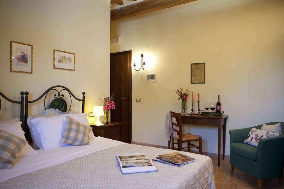 A bedroom with a bed, bedside table, lamp, and a chair.