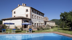 A large stone building with a swimming pool, outdoor seating, and a well-maintained garden. - Country House Parco Ducale (Urbania)