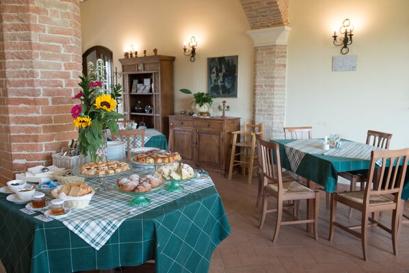 A dining area with a table set for a meal, surrounded by wooden chairs and a green tablecloth. - Country House Parco Ducale (Urbania)