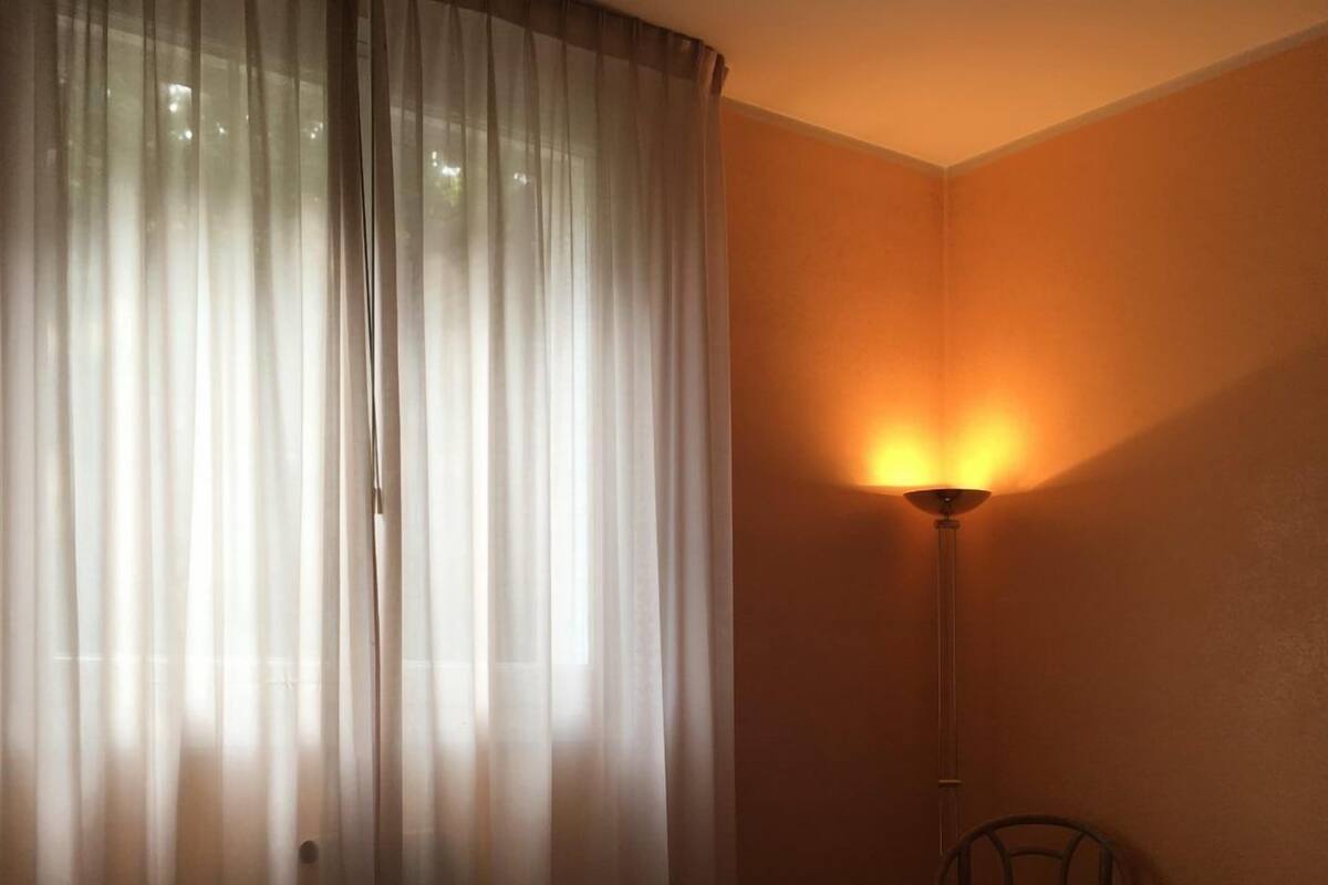 A hotel room with a bed, a table, and a lamp.