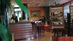 Un'accogliente hall d'albergo con una reception, comodi poltrona e un angolo caffetteria.