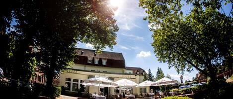 A restaurant with outdoor seating, a tiled roof, and a clear sky.