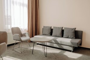 A modern living room with a sofa, two armchairs, and a round coffee table.