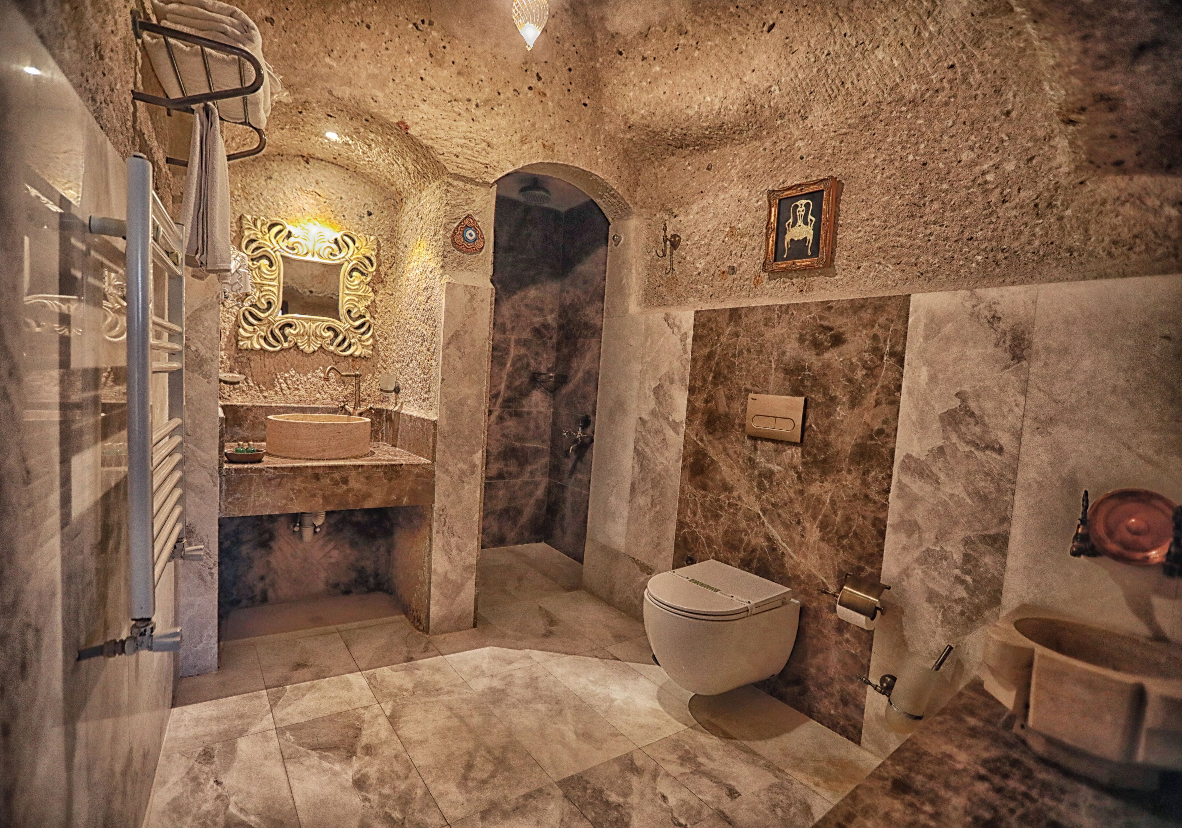 Un baño con suelo de mármol, lavabo, inodoro y zona de ducha.