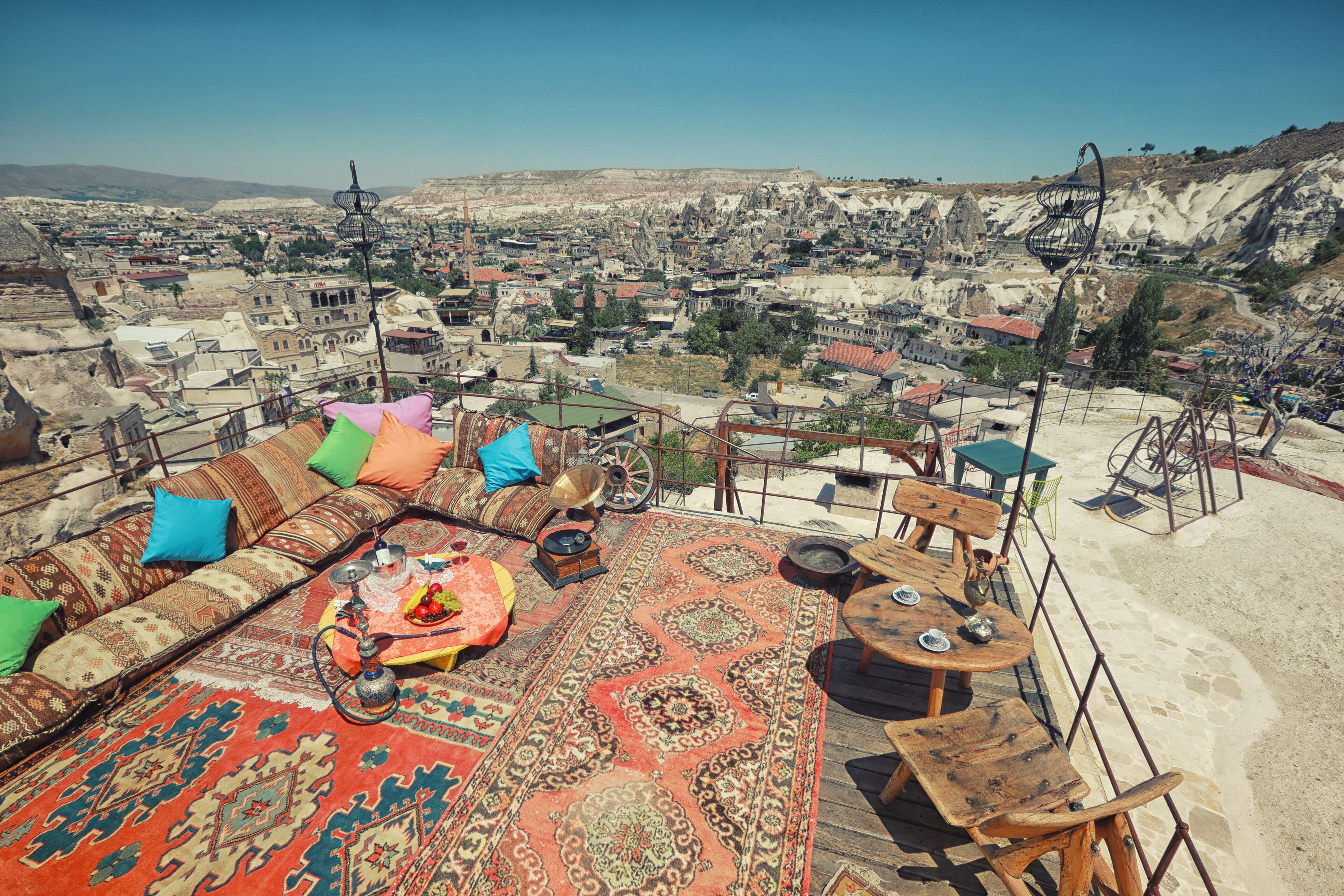 A rooftop terrace with a traditional rug, wooden furniture, and a hookah.