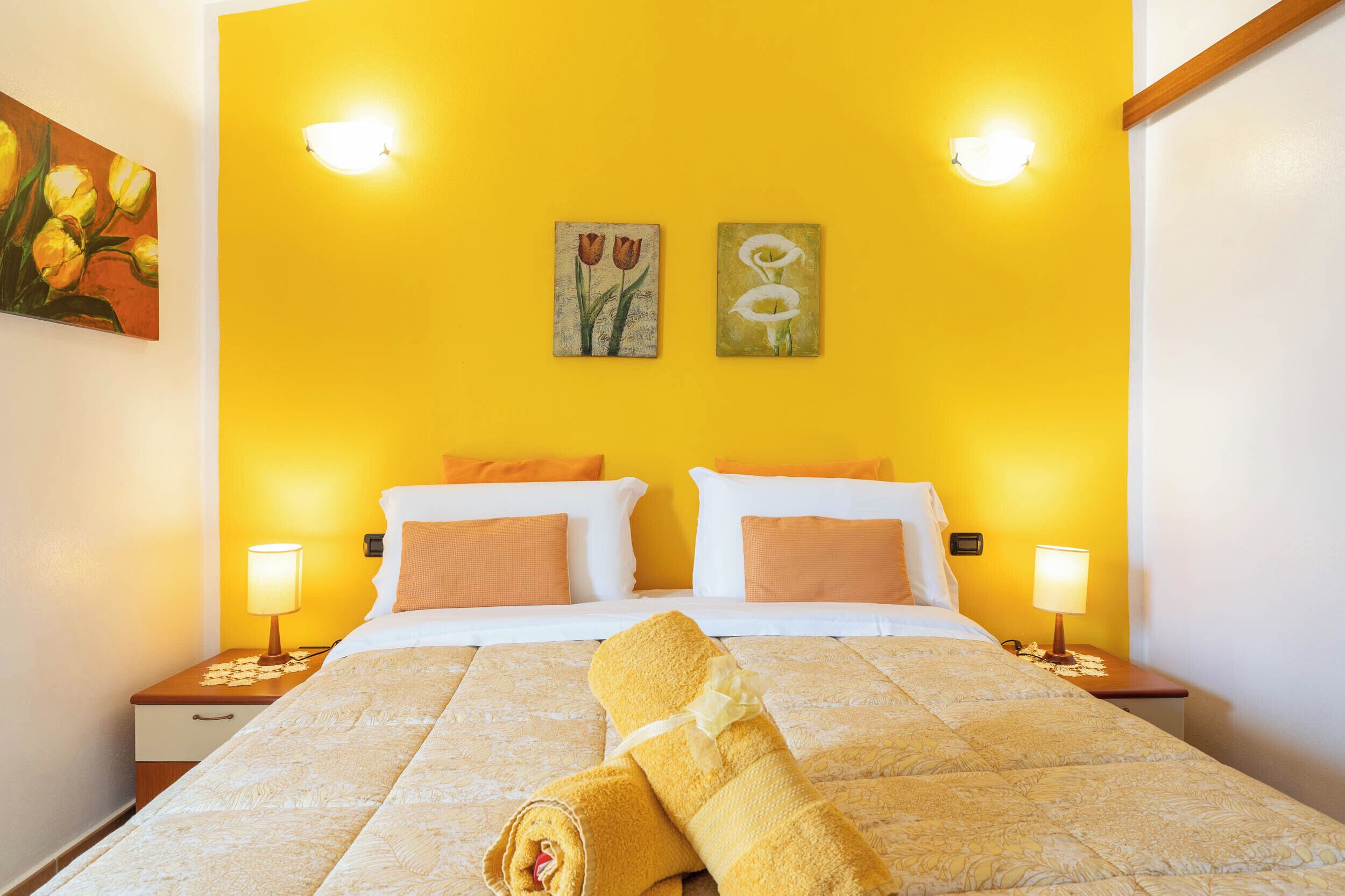 A hotel room with a bed, two bedside lamps, and two wall-mounted light fixtures.