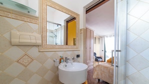 A bathroom with a white sink, mirror, and light switch.
