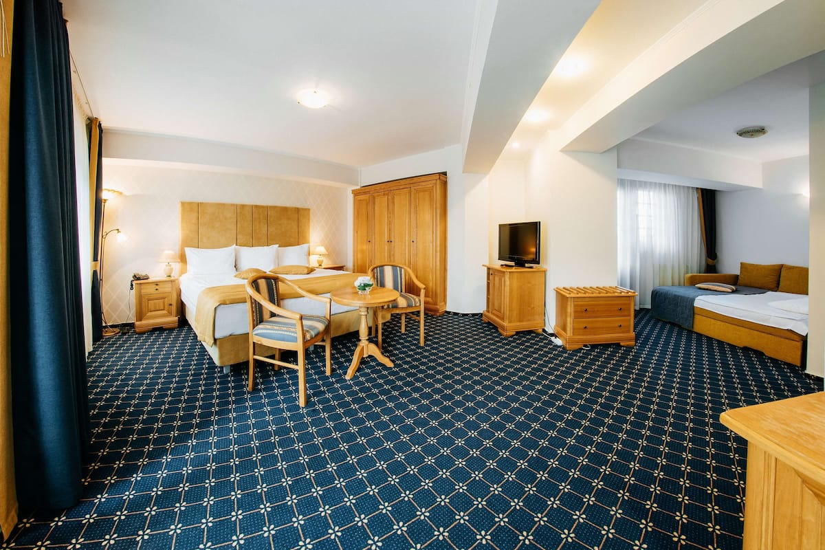 Une chambre d’hôtel avec un grand lit, un bureau avec une chaise, une télévision et une armoire.