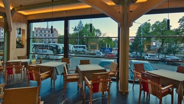 A restaurant with wooden interior and large windows offering a view of the street and parked cars. - Best Western Bucovina-club De Munte (Gura Humorului)
