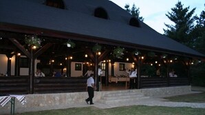 A covered outdoor area with a stone wall, wooden beams, and hanging lights. - Best Western Bucovina-club De Munte (Gura Humorului)