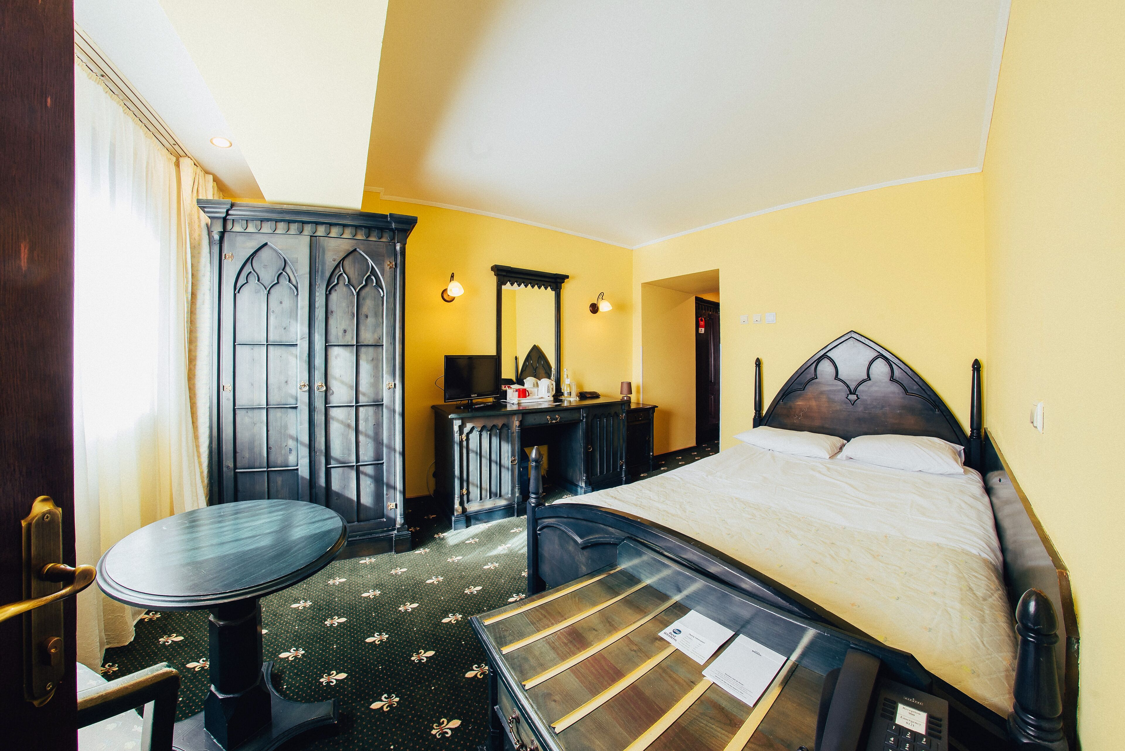 A hotel room with a bed, a desk, a chair, and a wardrobe.
