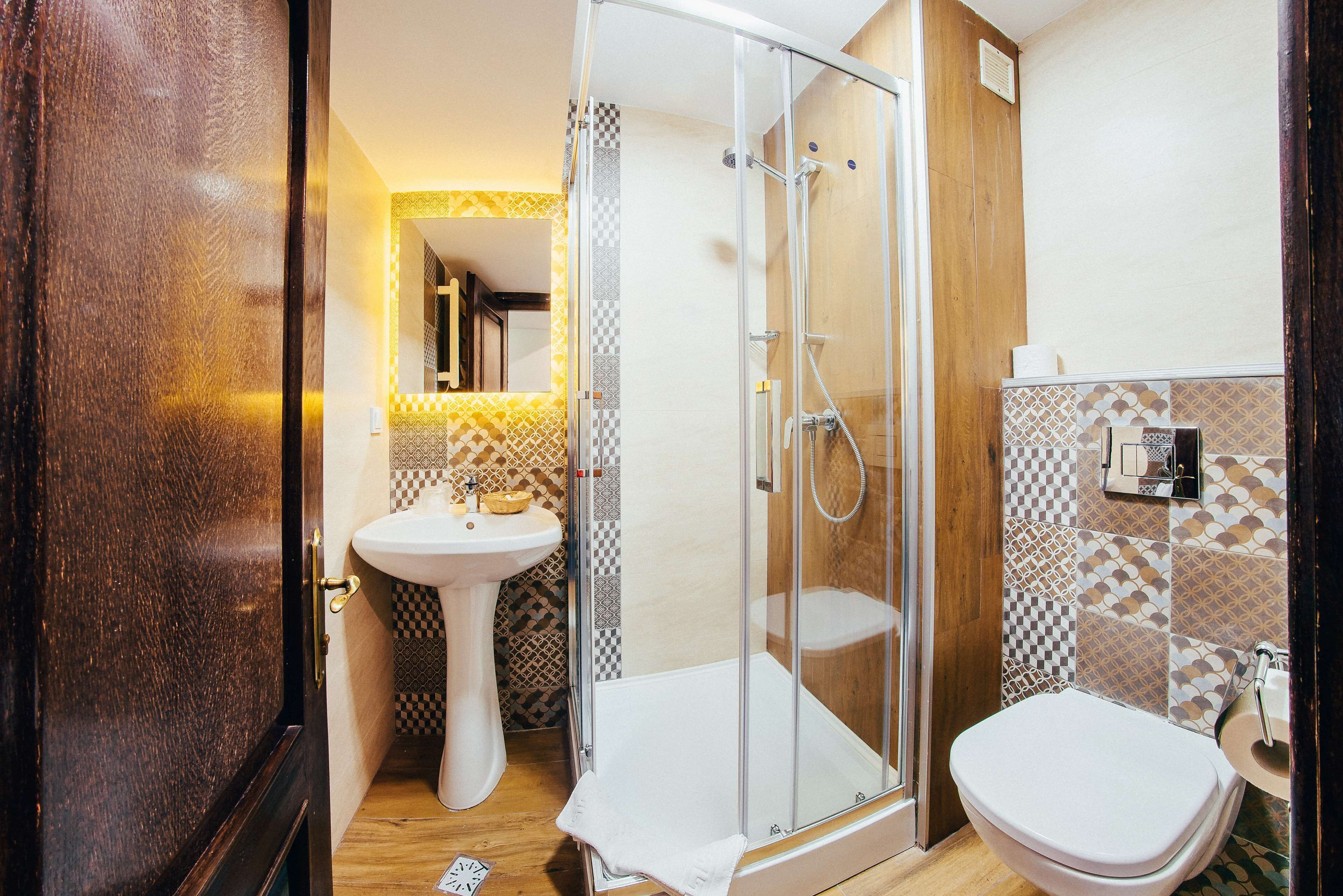 A bathroom with a glass-enclosed shower, a pedestal sink, and a toilet.