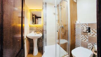 A bathroom with a glass-enclosed shower, a pedestal sink, and a toilet.