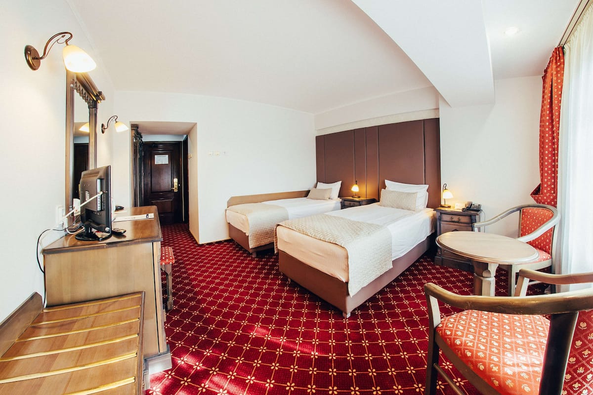 Une chambre d’hôtel avec deux lits, un bureau avec un ordinateur, une chaise et une petite table.