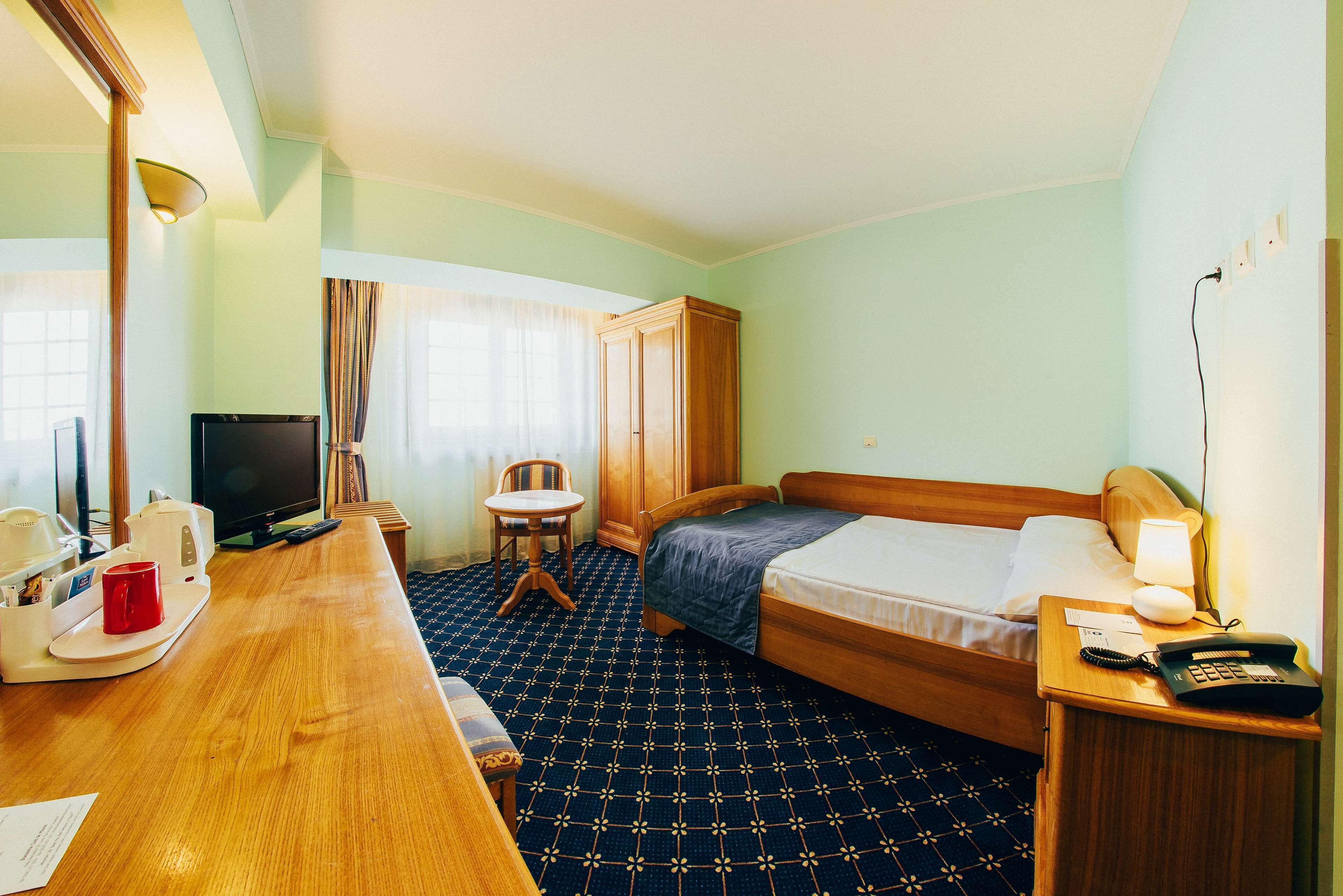 Une chambre d’hôtel comprenant un lit, un bureau avec un téléphone, une chaise, une télévision et une armoire.