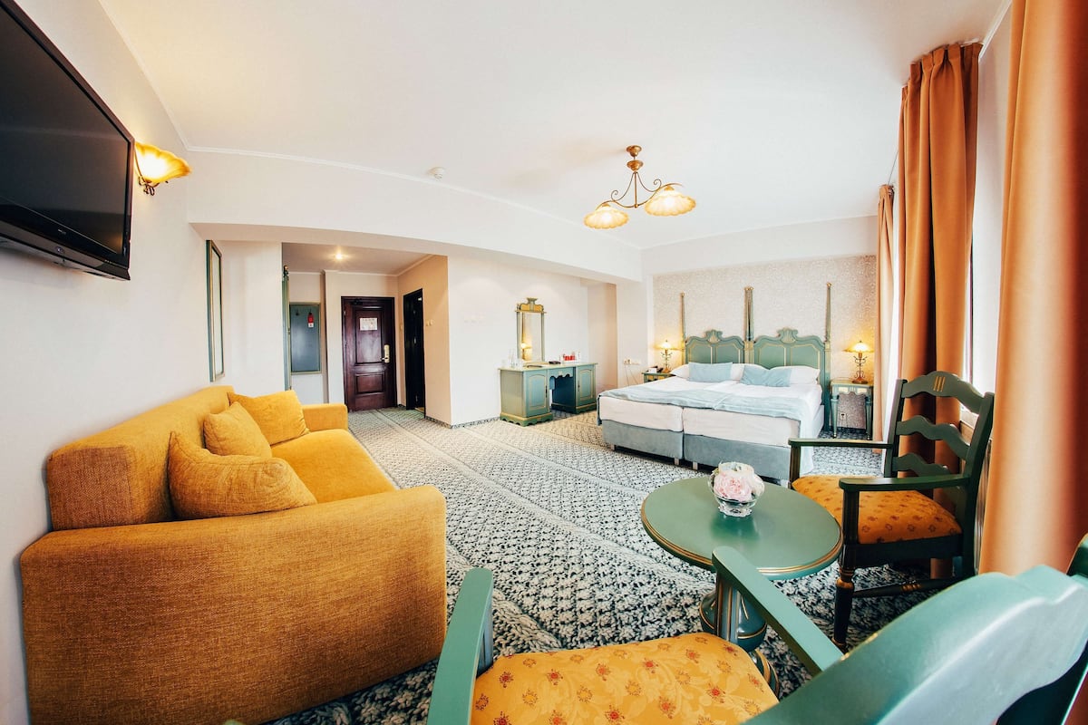 Une chambre d’hôtel avec un canapé, un lit, une table à manger et une chaise.
