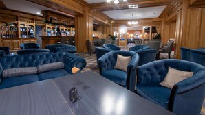 A bar area with wooden paneling, blue upholstered seating, and a bar counter. - Best Western Bucovina-club De Munte (Gura Humorului)