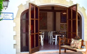 An open wooden door leading to a dining area with chairs and tables, a sign reading "Salón Natura", and a wall with artwork. - Hotel Puerta de Algadir (El Puerto de Santa Maria)
