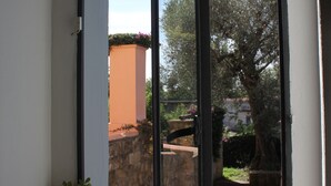 Una ventana con vista a un muro de piedra y un árbol.
