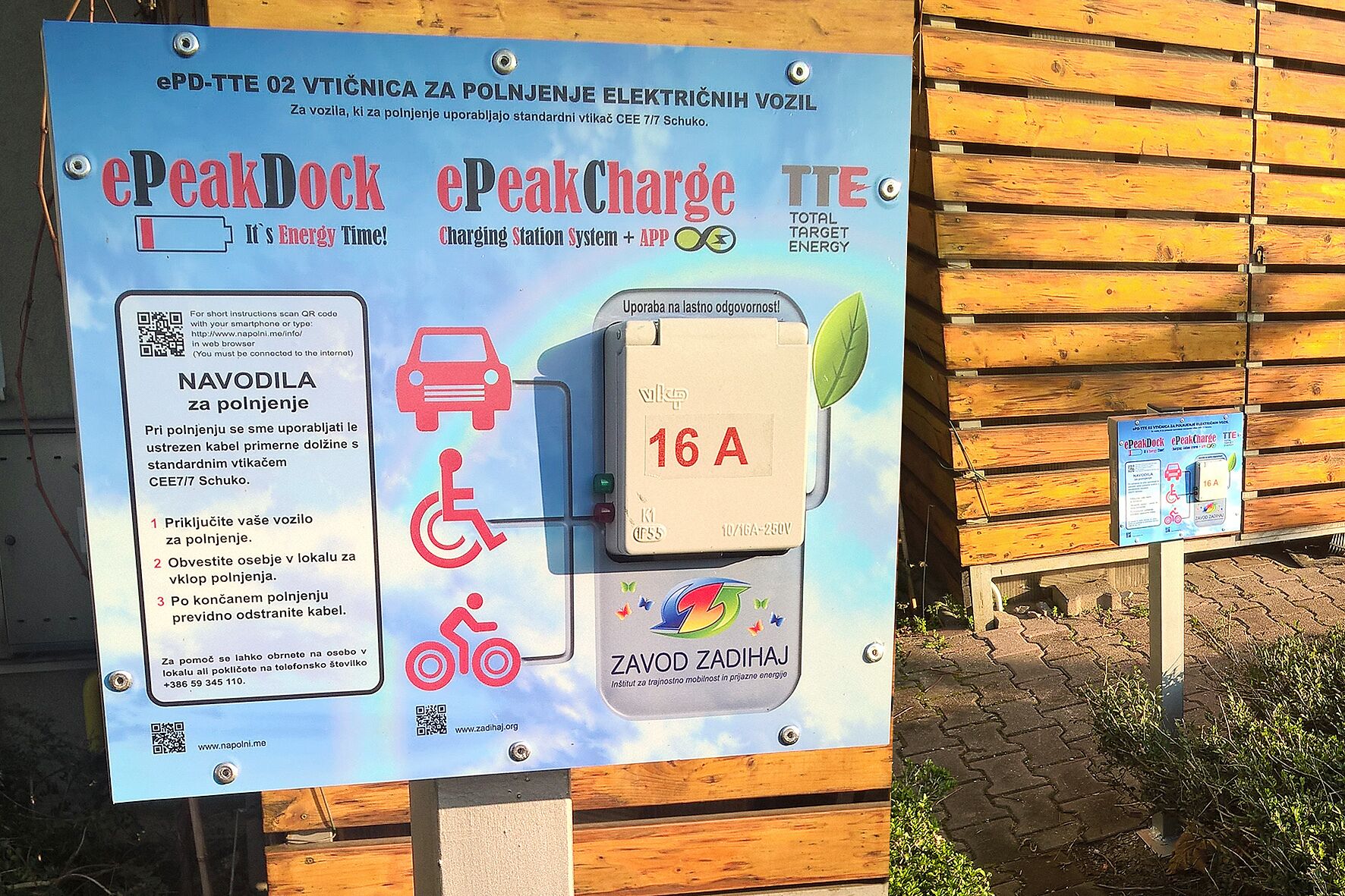 Een laadstationbord met instructies voor het opladen van elektrische voertuigen, inclusief een QR-code voor meer informatie.
