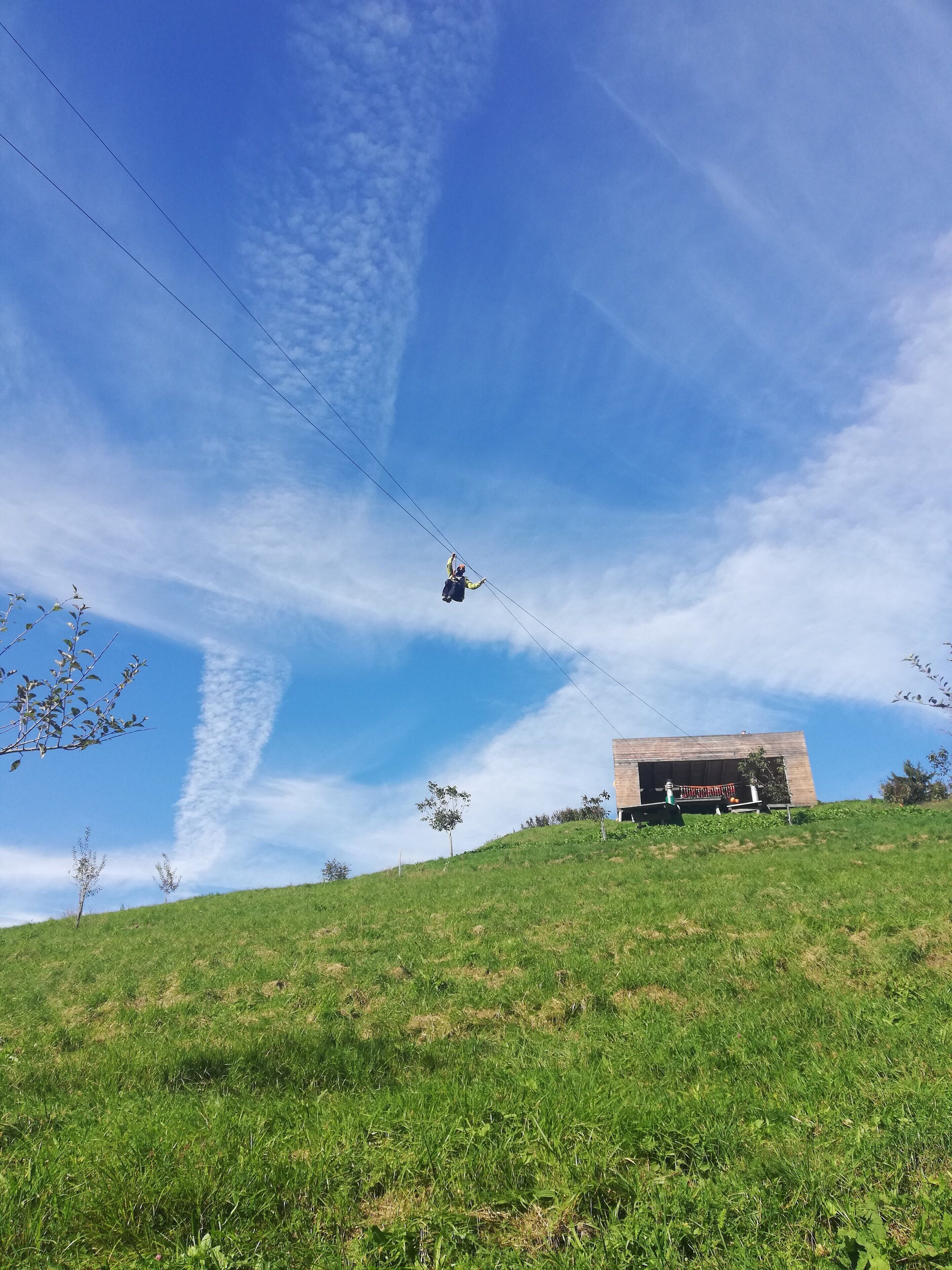 A grassy hill with a clear blue sky and a building in the background.