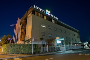 Un hotel con un letrero llamativo que dice "HOTEL TAROR" y un cartel de estacionamiento que indica una zona de estacionamiento.