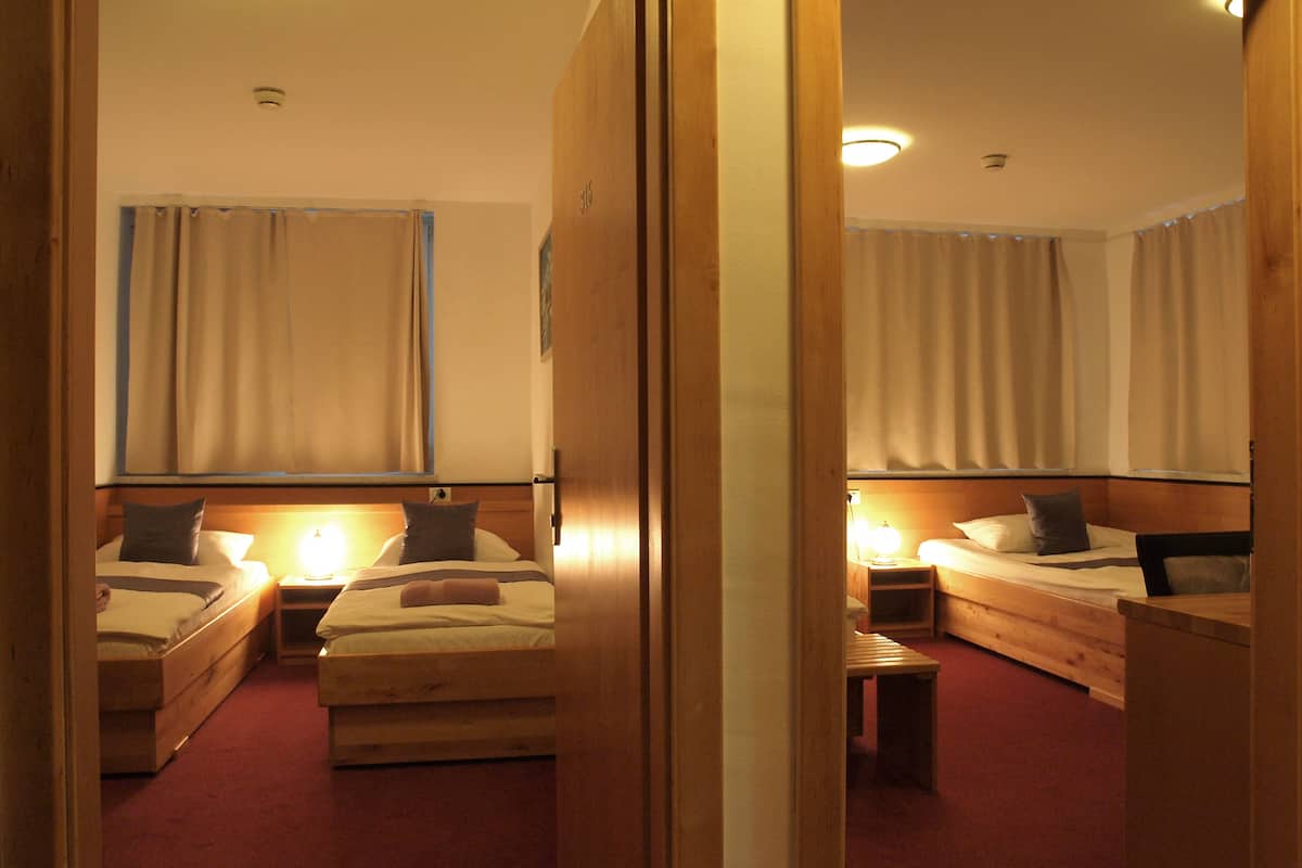 A hotel room with two single beds, a small table, and a mirror.