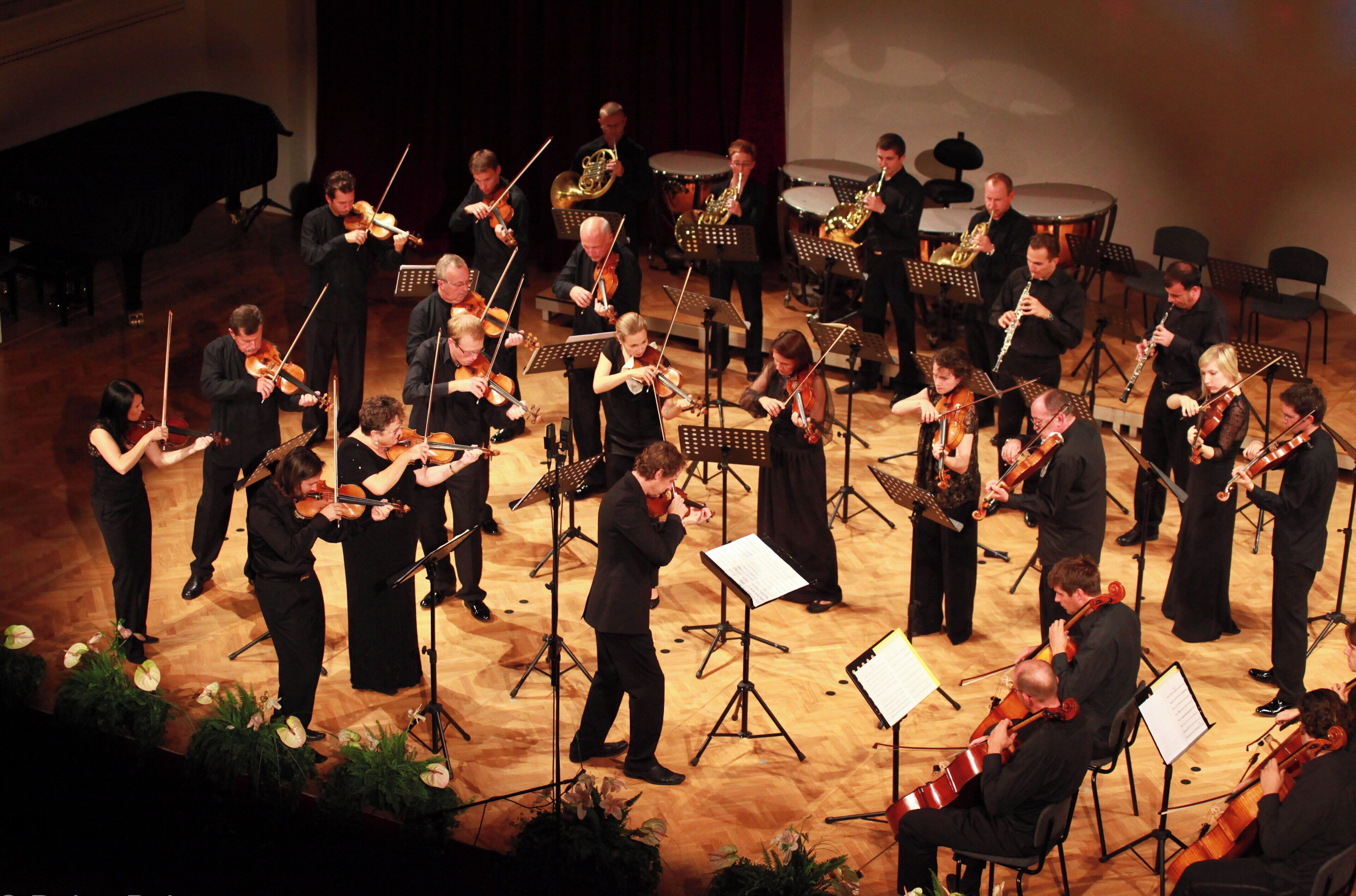 A group of musicians performing on a stage with music stands and sheet music.