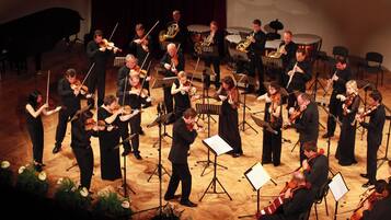 A group of musicians performing on a stage with music stands and sheet music.
