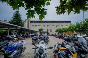 Un estacionamiento con varias motocicletas y un edificio al fondo.