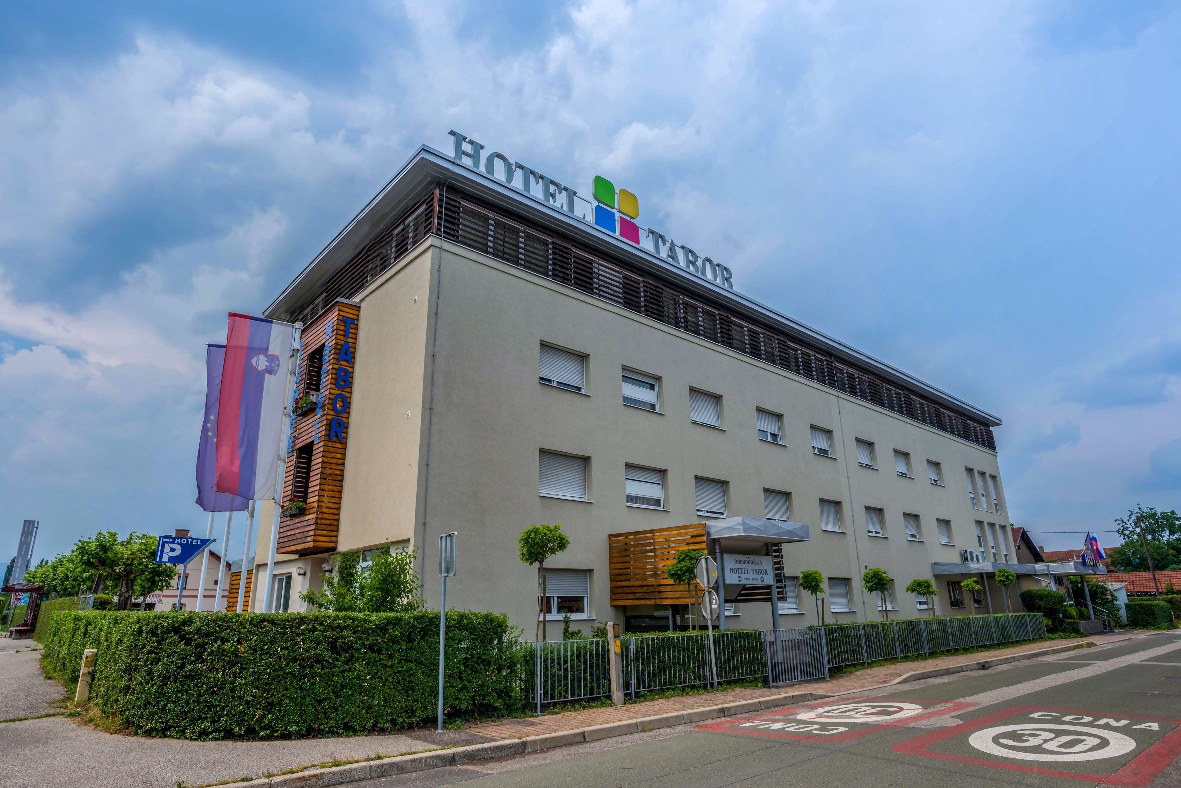 A hotel with a modern facade, multiple windows, and a sign indicating a parking area.