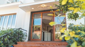 Entrada de un hotel con puerta de cristal, una escalera y un balcón.