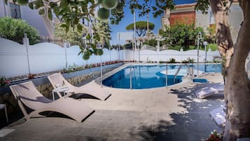 Una piscina al aire libre, tumbonas