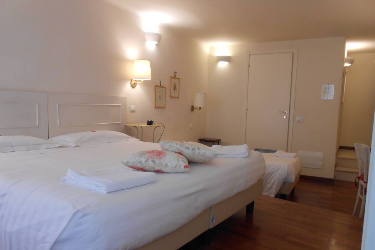 A hotel room with a large bed, two bedside tables, a chair, and a door.