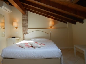 A bedroom with a bed, bedside lamps, a telephone, and a brick wall. - Albergo Atlantic (Bologna)