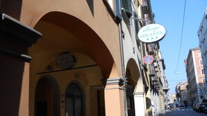 A street with a building featuring an arched entrance and a sign reading "albergo ATLANTIC". - Albergo Atlantic (Bologna)