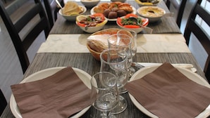 Una mesa de comedor dispuesta con varios platos, vasos y servilletas.