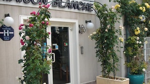 Exterior del Hotel Maison Blanche con un cartel que indica que es un hotel turístico.