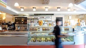 Un comptoir de boulangerie où sont exposés divers produits de boulangerie, et une personne qui passe.