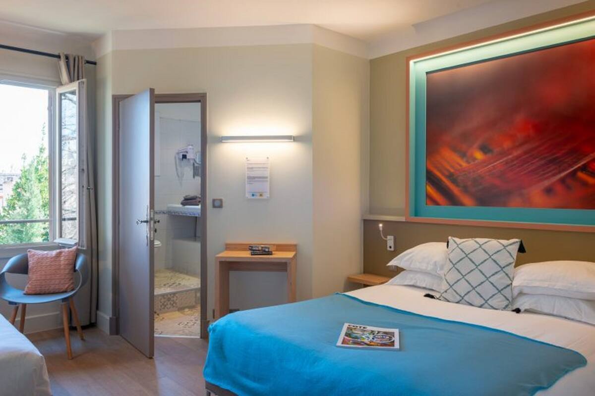 Habitación de hotel con una cama, un escritorio, una silla y un cuadro abstracto grande en la pared.