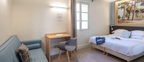 A hotel room with a bed, a desk, a chair, a sofa, and a painting on the wall.