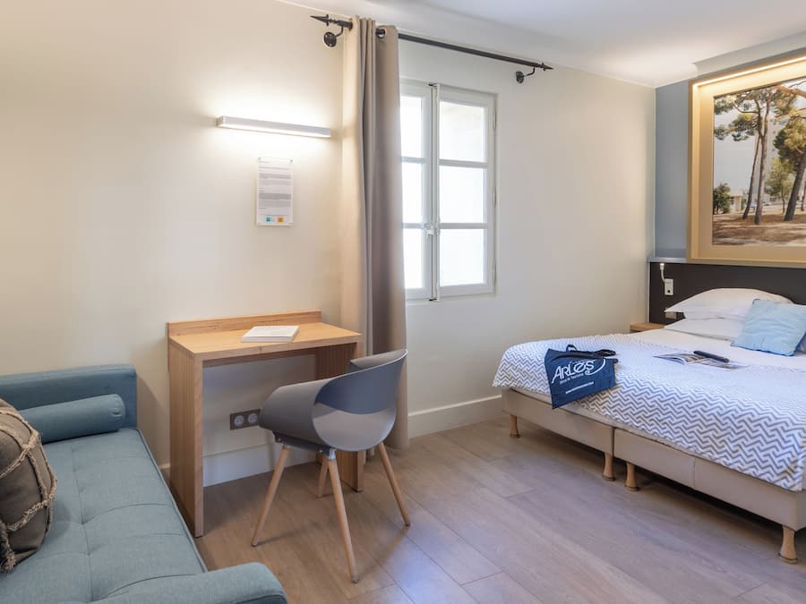 Een hotelkamer met een bed, een bureau, een stoel, een bank en een schilderij aan de muur.