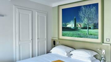 A hotel room with a bed, a window with a view of a garden, and a telephone on the nightstand.