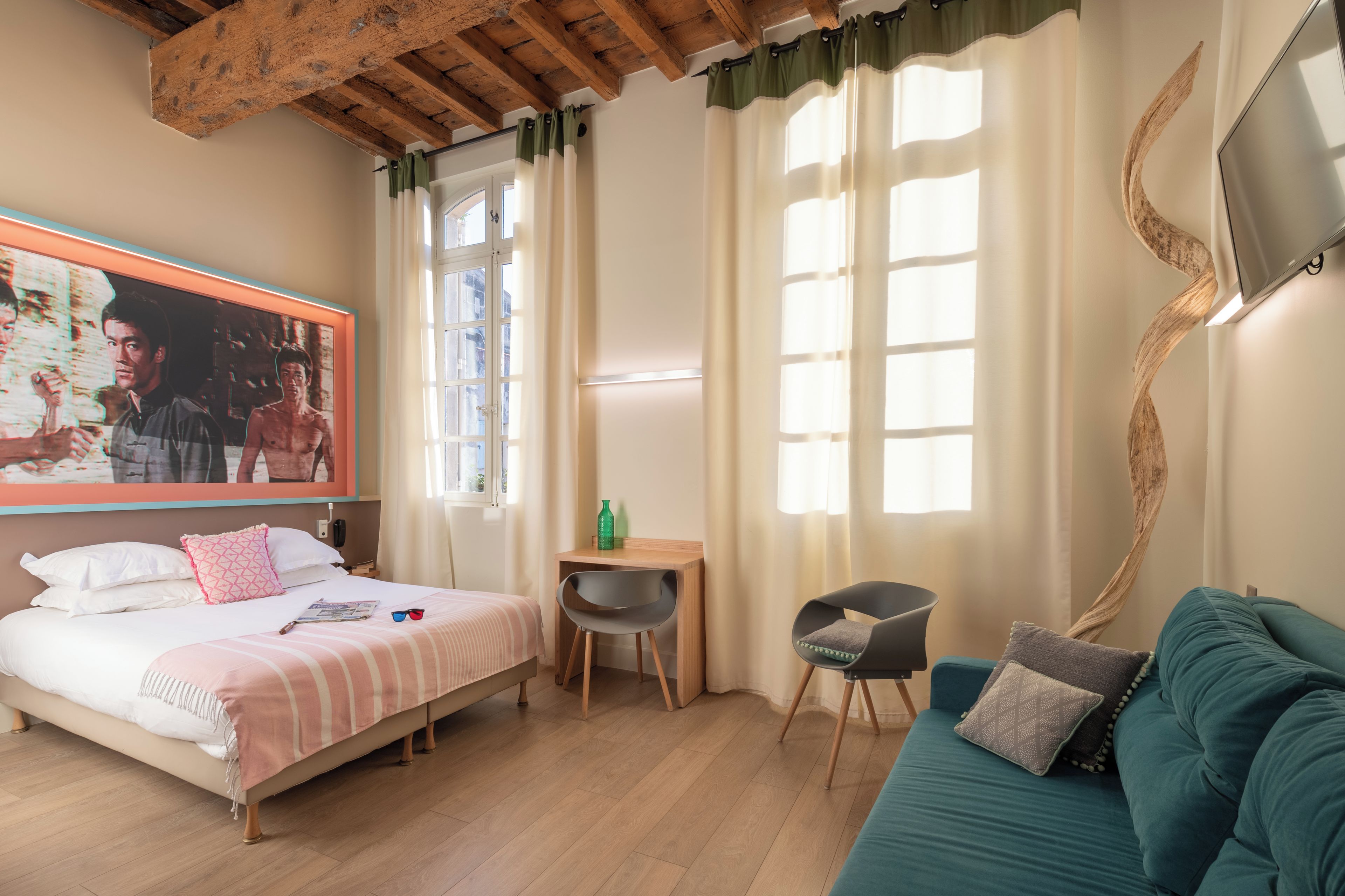 A hotel room with a bed, a desk, a chair, a sofa, and a TV.