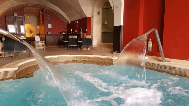 Un bain à remous avec jets d’eau, un espace d’accueil doté d’un comptoir et de chaises, et un sol carrelé.