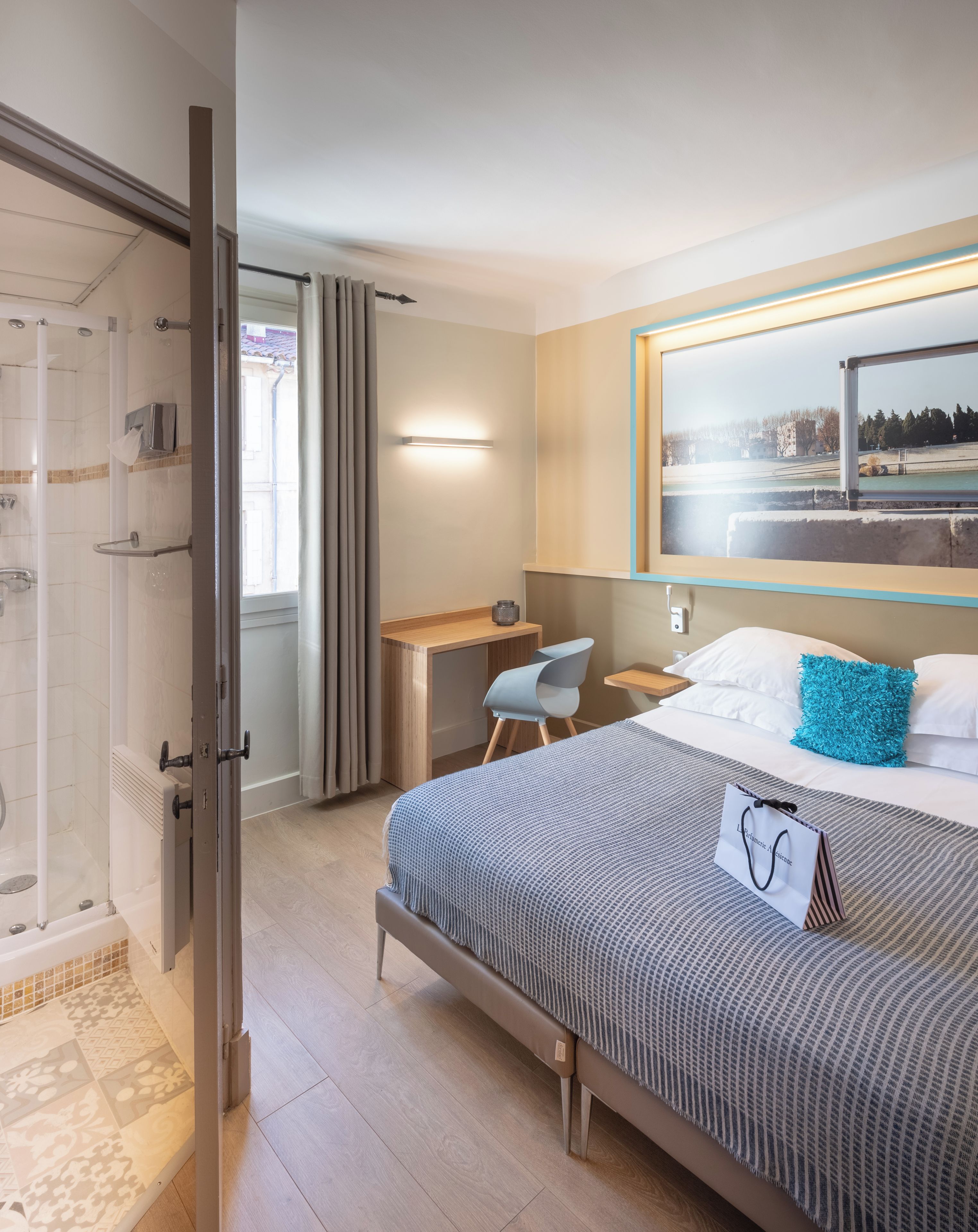 Hotellihuone, jossa on sänky, työpöytä, tuoli ja suihkutila.